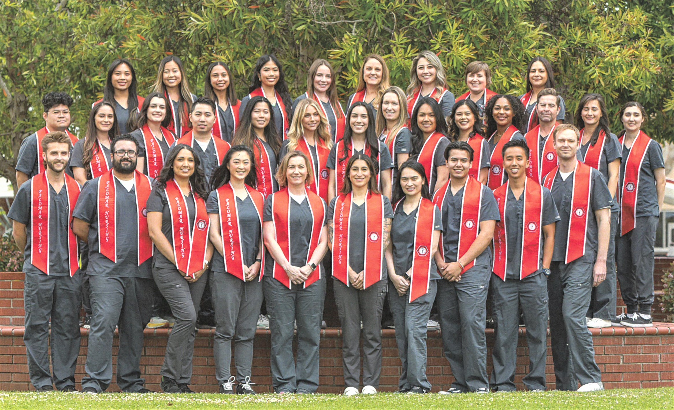 group photo of nursing students wearing scrubs and graduation stoles