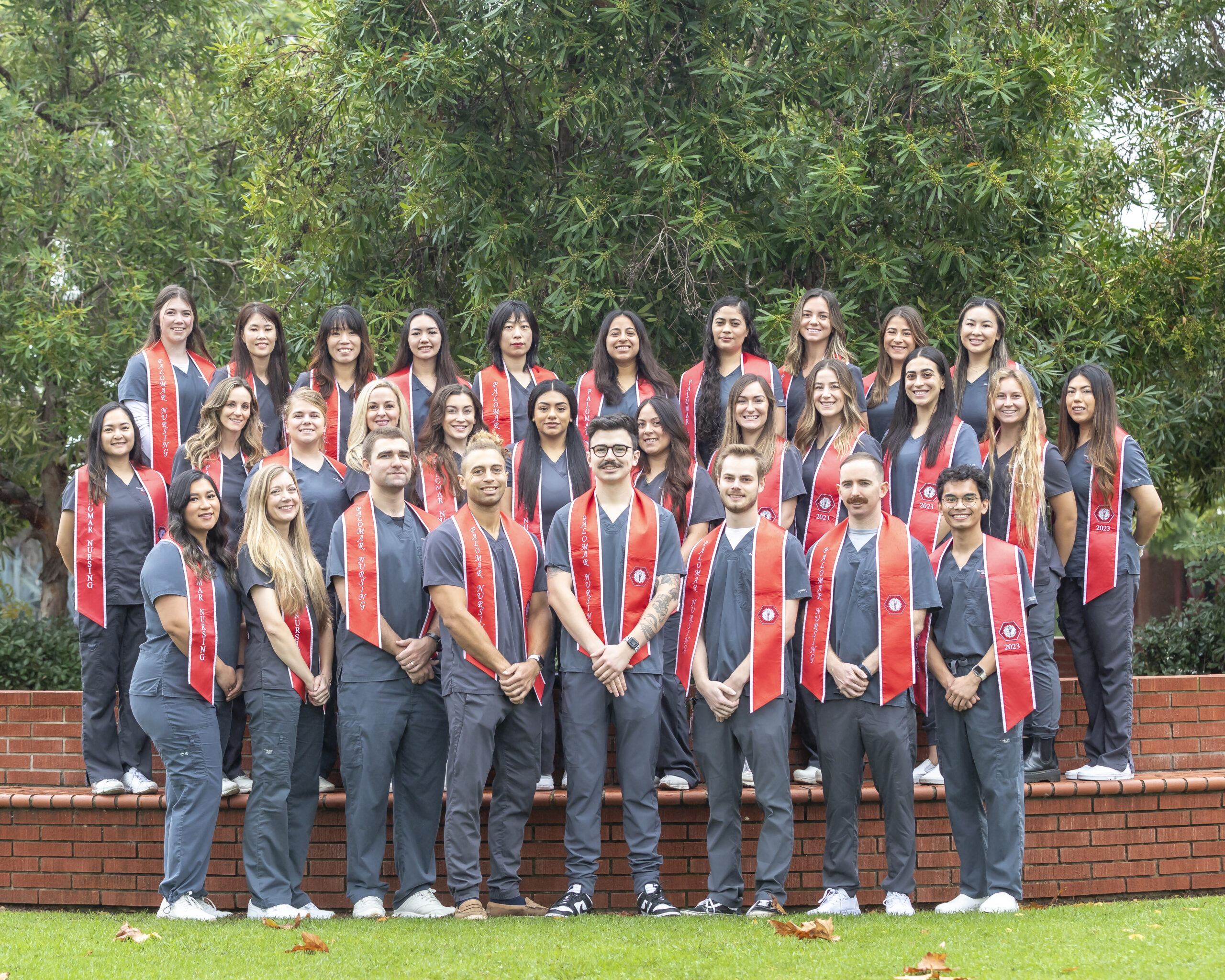 group photo of nursing students wearing scrubs and graduation stoles