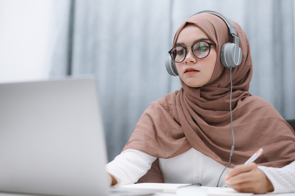 Asian muslim student using a laptop computer learning online at home.