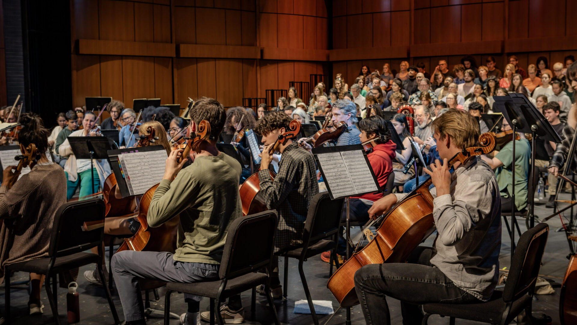 A photo from the production "Ode to Joy". Onstage you see an orchestra playing various insturments and behind them stand a choir.