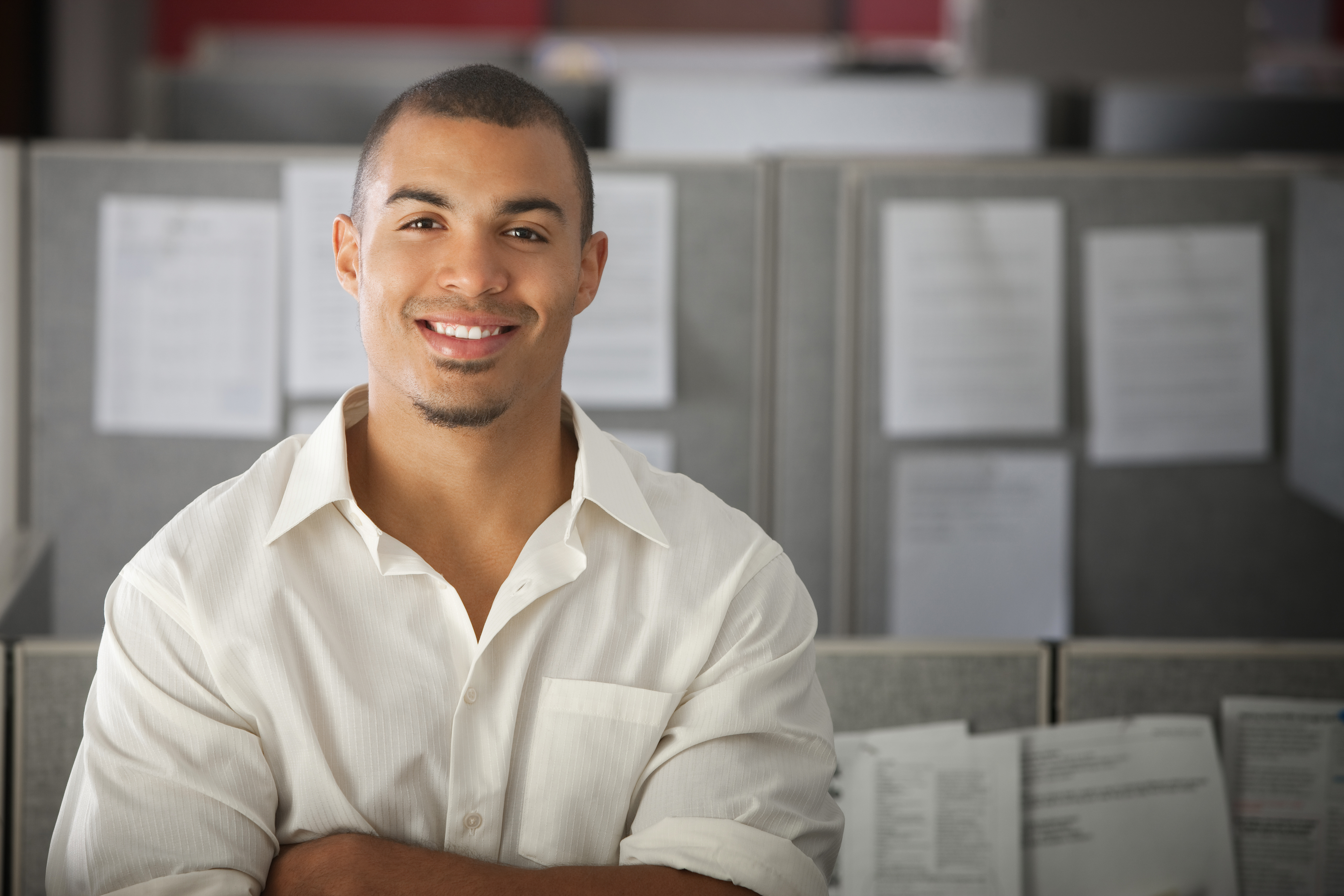 Confident office worker smiles in his office cubicle