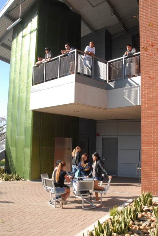 Group of students at a table and hanging out in a balcony of the Health and Sciences building 