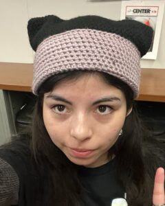 Emily is wearing a black Palomar Promise shirt and a knitted hat with cat ears
