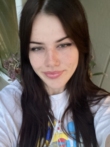 Eva is smiling at the camera in a white shirt. 