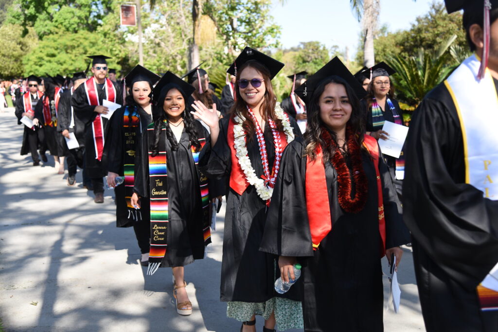 Palomar College graduates walking in a line and smiling at the camera.