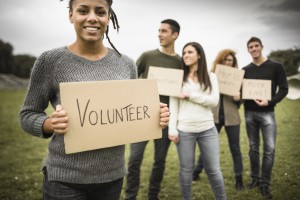 Photo of five young people, one holding sign that says "Volunteer"