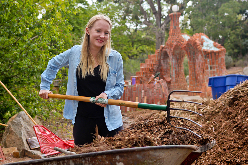 Madison Power, a STEM Ambassador, rakes mulch into a wheelbarrow at the Spring 2016 Arboretum Beautification Day on April 30. Michaela Sanderson/The Telescope.