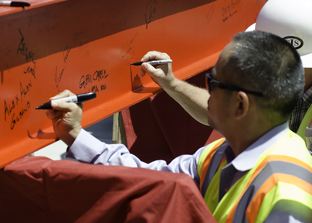 Gilbane's Executive Project Manager Alex Along and fellow construction worker from CIS sign the final beam before it was hoisted and bolted into the new Library/Learning Resource Center during the Topping Out Ceremony held on July 28 at the San Marcos campus. Tracy Grassel/The Telescope
