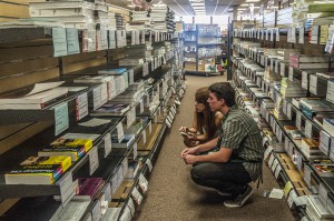 Sales Associate Ryan Pell (lower right) assists student Maika Takayabu (left) locate a book for her GCIP class at the Palomar College bookstore. On Sept. 16, 2013. • Lucas Spenser | The Telescope File Photo 