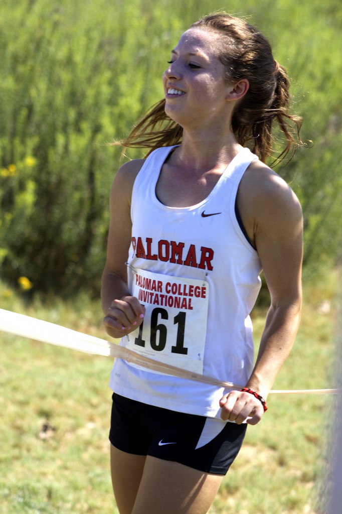 Palomar College Cross Country Invitational at Guajome Park. Sophomore runner and winner Jessica Steinhoff #161, is showing a big Smile of pride as she breaks through the finish line tape. Steinhoff remained in the lead throughout the race, several times having a large separation ahead of the other runners. Palomar College Jessica Steinhoff won the race and demonstrated her hard work and pride as a cross country runner. Steinhoff placed first place with a finish time of 20:08