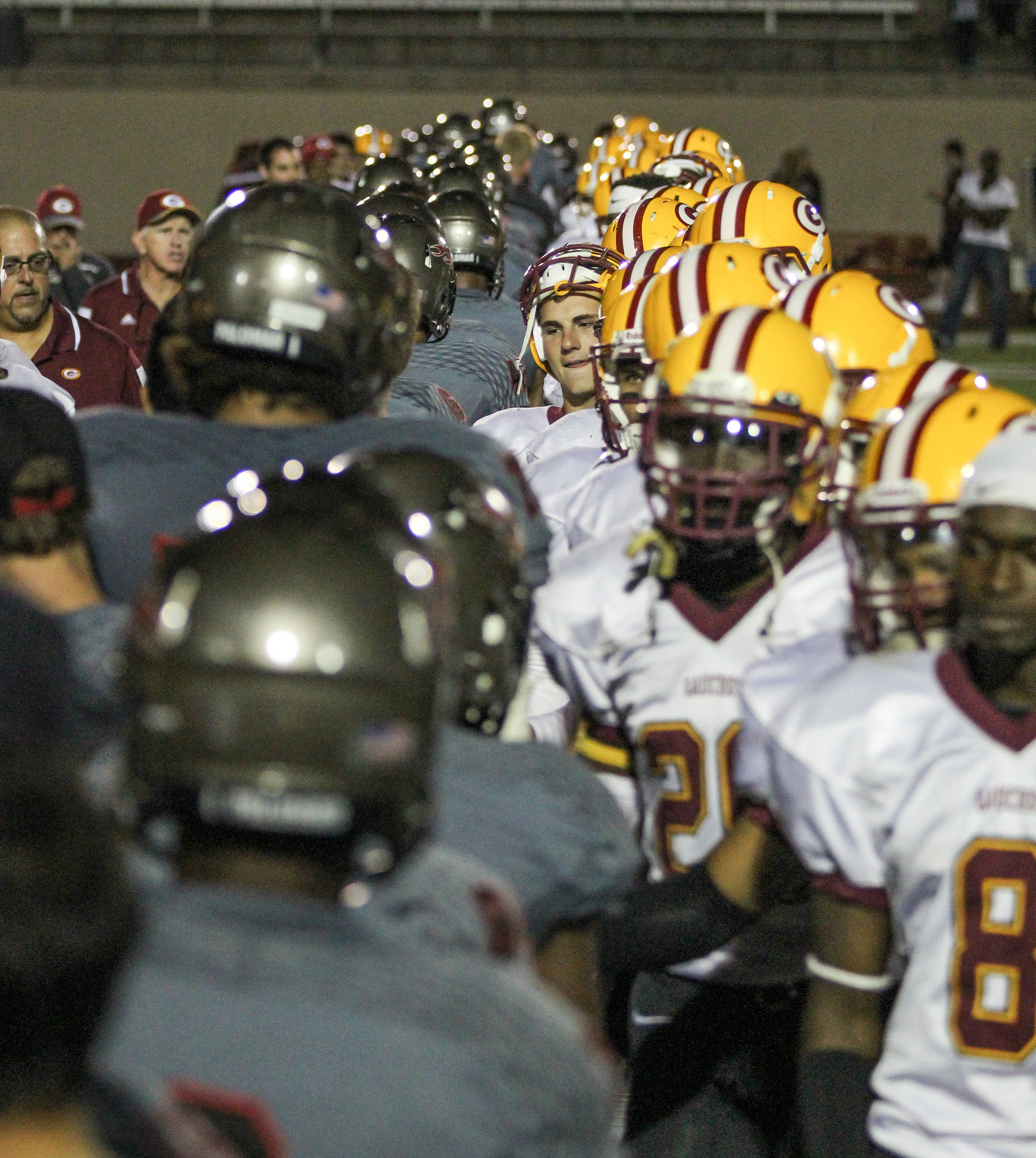Palomar football players (left) shakes hands with Saddleback players, each team forming a line.