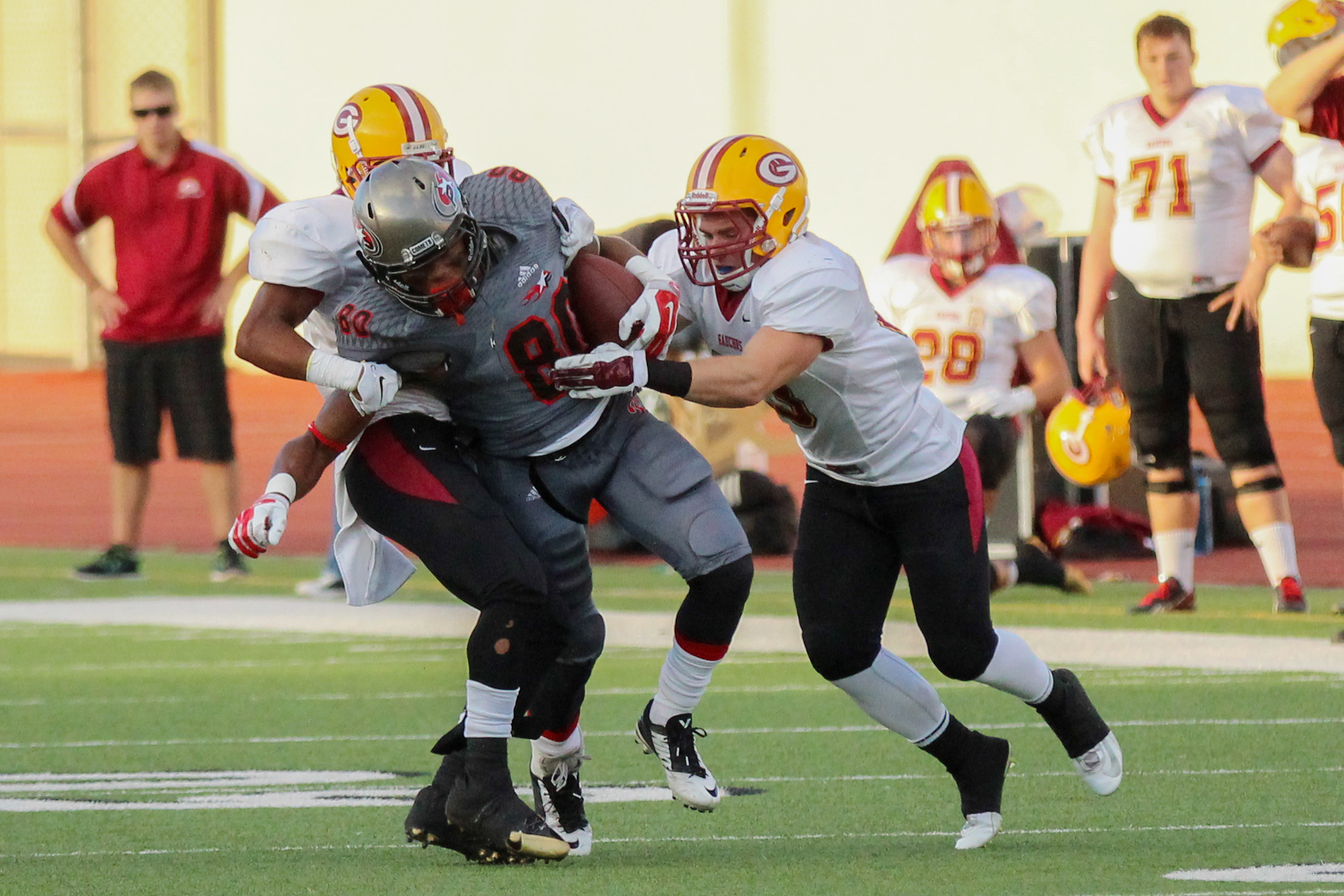 Two Saddleback football players tackle a Palomar football player.