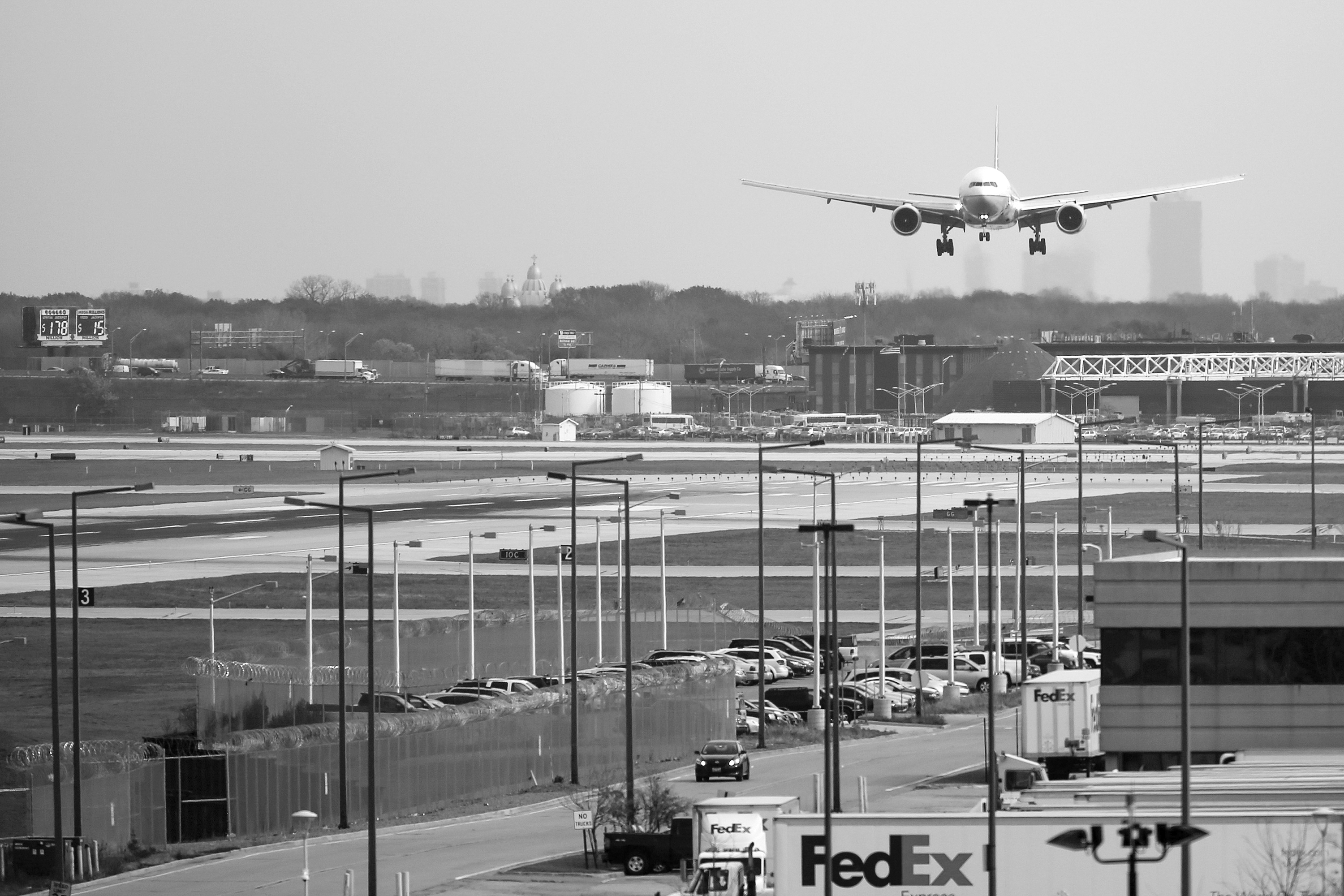A commercial airplane starts to land on a runaway. Black and white photo.