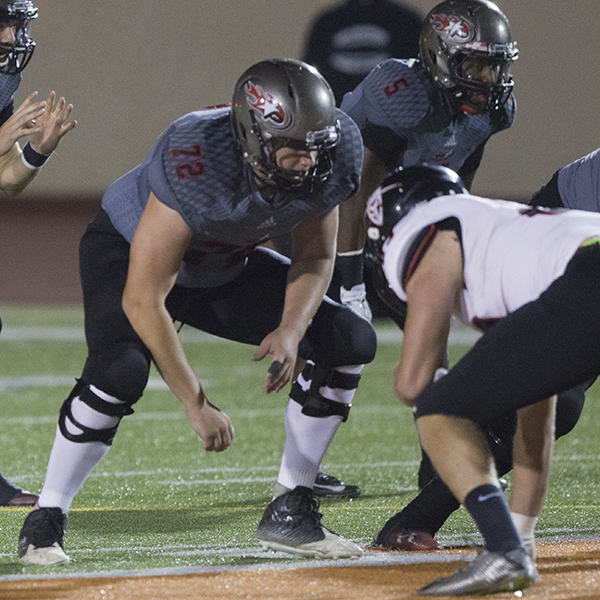 A Palomar football player gets ready to tackle his opponent with several team players to his sides.