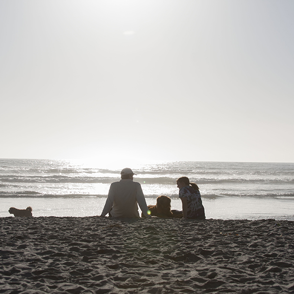 North County locals, Doug Mau and daughter, relax on the sand accompanied by the family dogs during an April afternoon at Dog Beach, Del Mar. Claudia Rodriguez/The Telescope