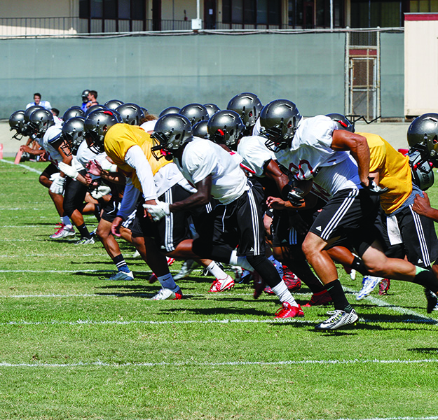 A team of Palomar football players runs on a field.