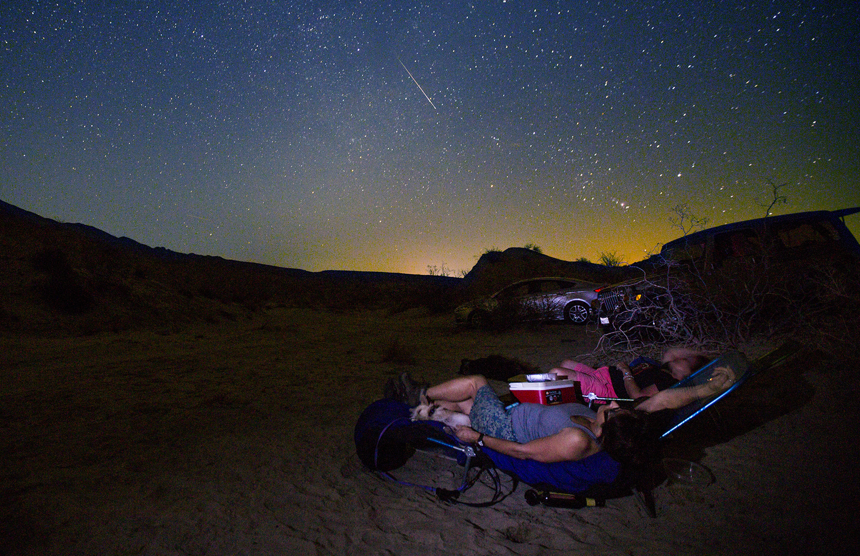 College photography professors Donna Cosentino and Judith Preston watch a Persied meteor streak through the starry sky above California's Anza Borrego Desert State Park on Thursday, Aug. 13, 2015. The orange glow is from the lights of Salton City, about 10 miles away. Scores of the "shooting stars" were observed during the annual skyshow when Earth passed through interplanetary matter from an orbiting comet. (Don Bartletti/Los Angeles Times/TNS)