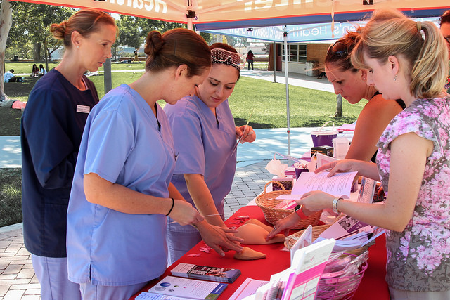In observance of National Breast Cancer Awareness Month Emily Andraejewski and Lenka Schalkle (far right, left to right) of Palomar College Student Health Services explain the methods of breast self-exams to registered dental assistant students Monique Leibee, Christina Asmus and Amanda Tabikha (far left, left to right) at a display adjacent to the student union. Oct. 13, 2015. By Lou Roubitchek / The Telescope
