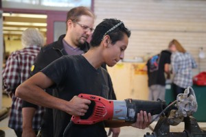 Professor Ingram Oberstands behind student Ricardo Baza, guiding him in the process of cutting his bronze scuplutre with a specialized saw on Dec. 2. in the art department. Michaela Sanderson/The Telescope