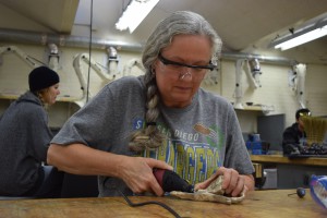 Debra Crandall using a file for the finishing touches on her bronze piece on Dec. 7. in the art department. The result of her work was a sculpture of a bird resting on a branch. Michaela Sanderson/The Telescope