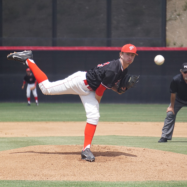 A male Palomar baseball player pitches a baseball with his right hand as his right leg extends behind him.