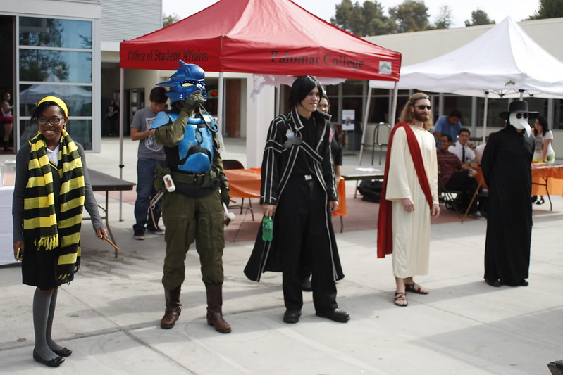 Five students stand next to each other during a Halloween costume contest (l-r): a bee-like outfit, a blue-mask character, Kylo Ren, Jesus, and a plague doctor.