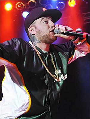 Hip-hop artist Mac Miller performs and holds a microphone to his mouth.