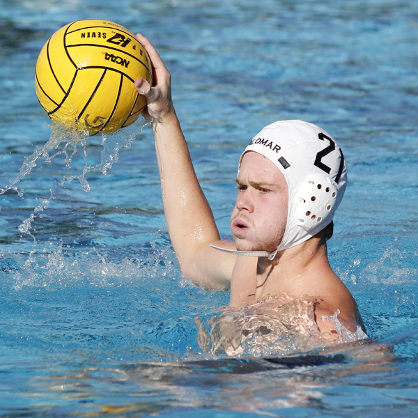 A male Palomar water polo player gets ready to throw a ball with his right hand.