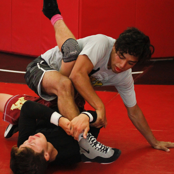 Two male Palomar wrestlers tackle each other on the ground.