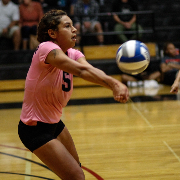 Palomar volleyball player Kianna Niu bumps a ball with both forearms. She wears a pink jersey and black shorts.
