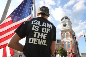 A young man stands across from the Covington courthouse during a protest against building a mosque in Newton County on September 13, 2016, in Covington, Ga. (Curtis Compton/Atlanta Journal-Constitution/TNS)