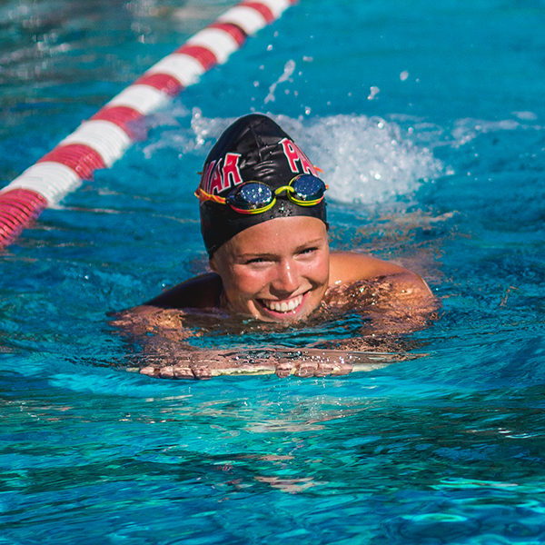 Emma Thomas smiles and swims in the pool during practice.