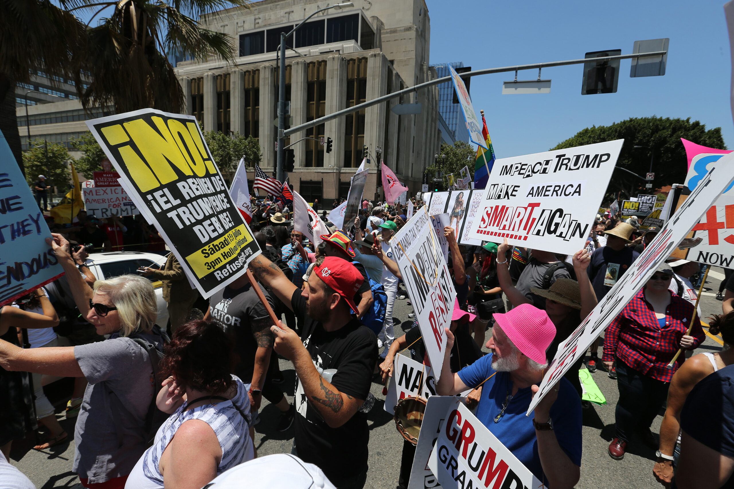 Many protesters stand in a street, holding various signs in Pershing Square, Los Angeles.