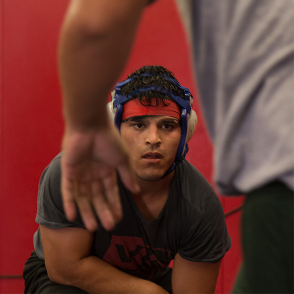 A male Palomar wrestler crouches in front of his opponent as they prepare for a match.