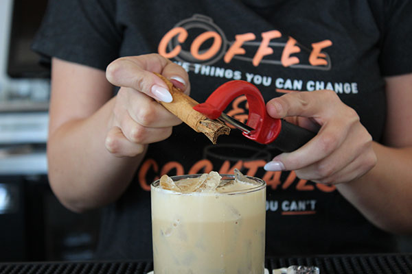 Halcyon employee garnishes the Cosmonaut with cinnamon shavings. The new San Marcos bistro opened this fall with a menu containing coffee, mixed drinks, and artisianal sandwiches. Seji Gaerlan/The Telescope