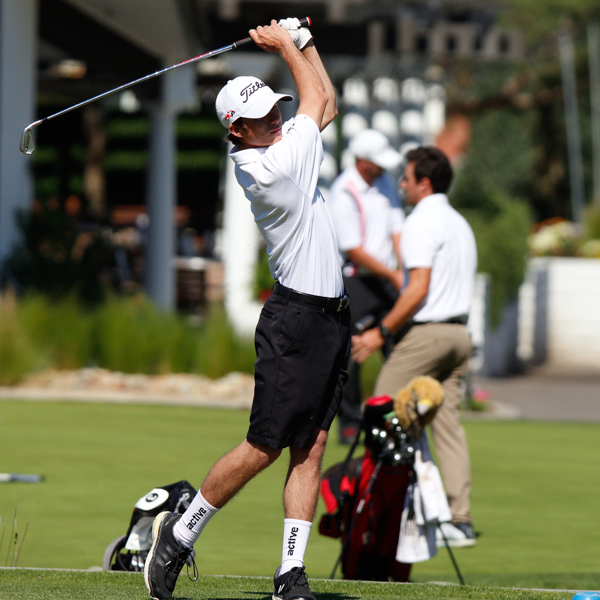 Palomar golfer Pat Gorman swings a golf club over his left shoulder. He wears a white cap, a white shirt, and black shorts.