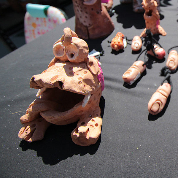 Clay sculptures of a frog-like creature and severed fingers on a table covered by a black cloth.