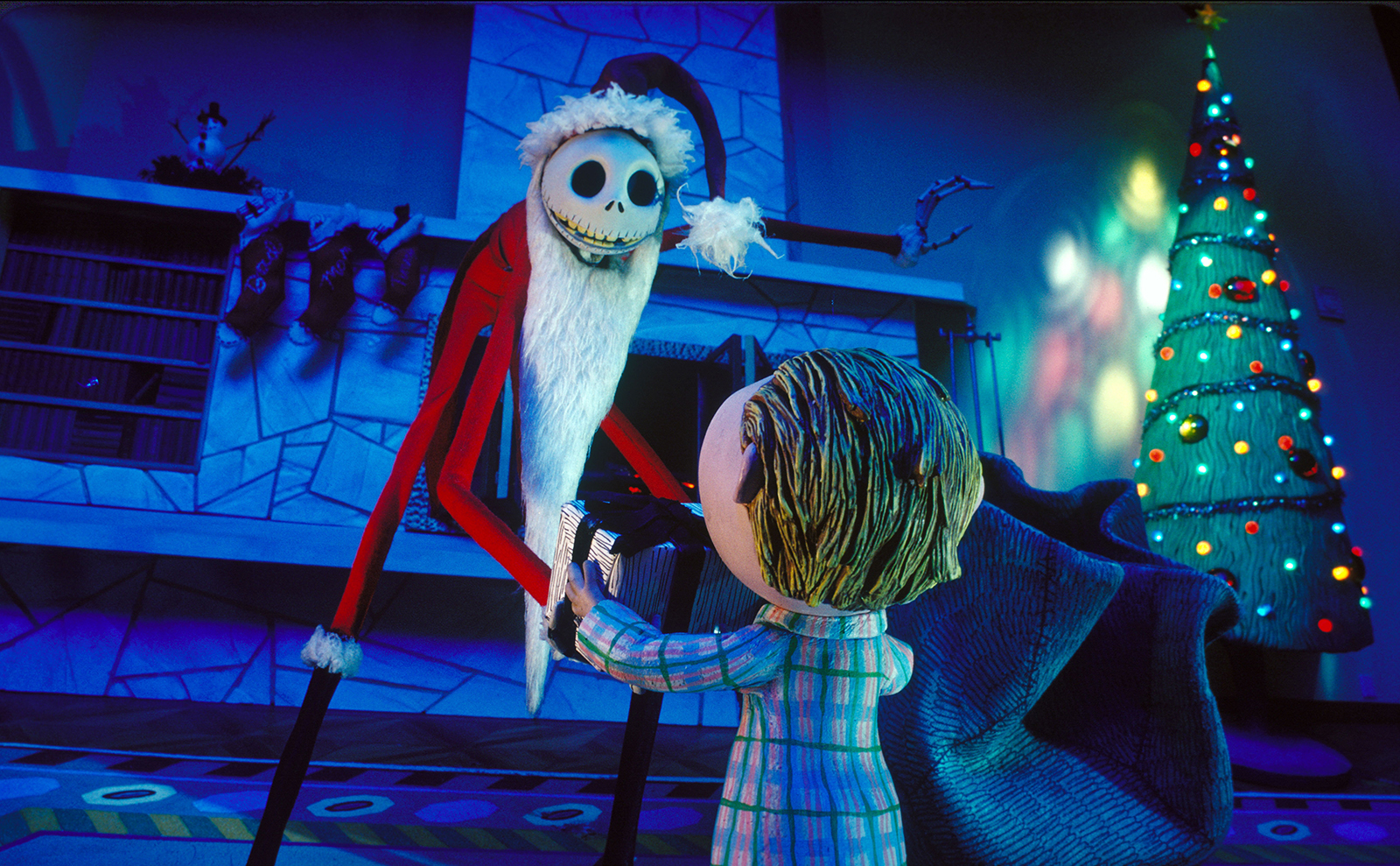 A skinny skeleton wearing a Santa suit gives a gift to a child with a Christmas tree on the right side.