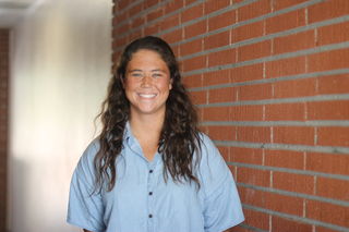 Palomar Water polo captain Kelly Rowan stands and smiles, wearing a light blue buttoned shirt.