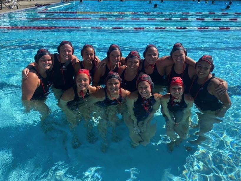 A group of Palomar female water polo players pose for a photo in a swimming pool.
