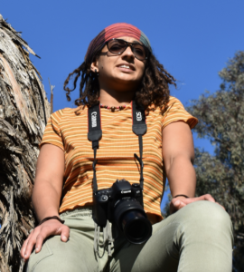 Image of Trina McLeary in a tree with a camera around her neck.