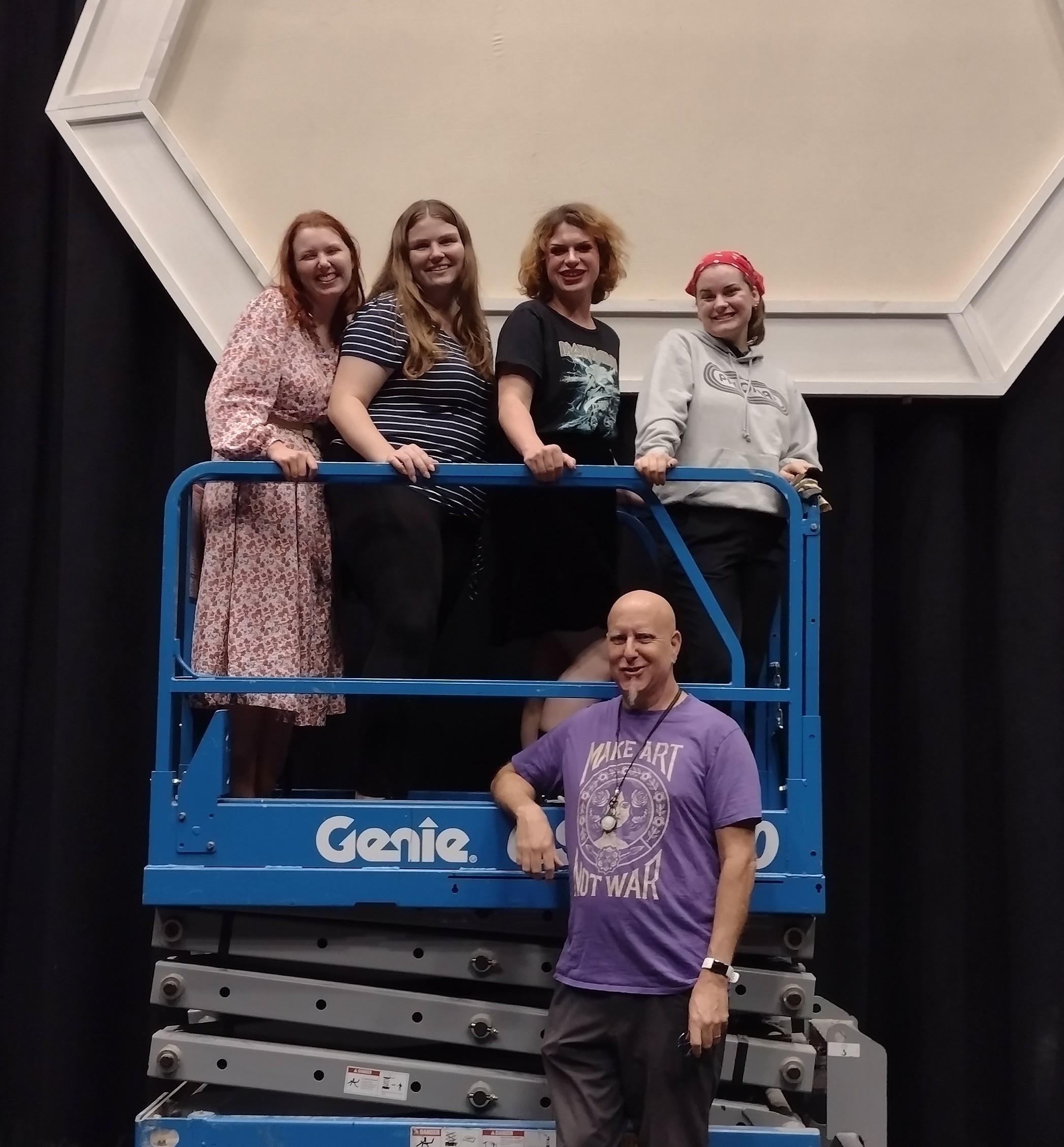 Four of the six cast members from "Greetings from the Red Planet" pose on a blue automatic-lift platform above director, Michael Mufson.
