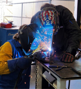 Professor Ashley Wolters supervising student's weld.