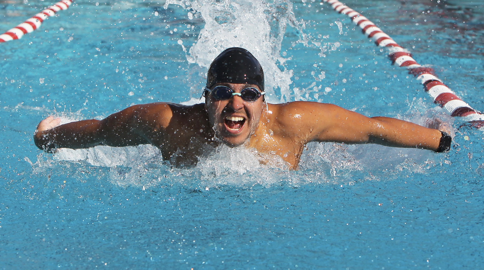 A man swims in a pool with a butterfly stroke.