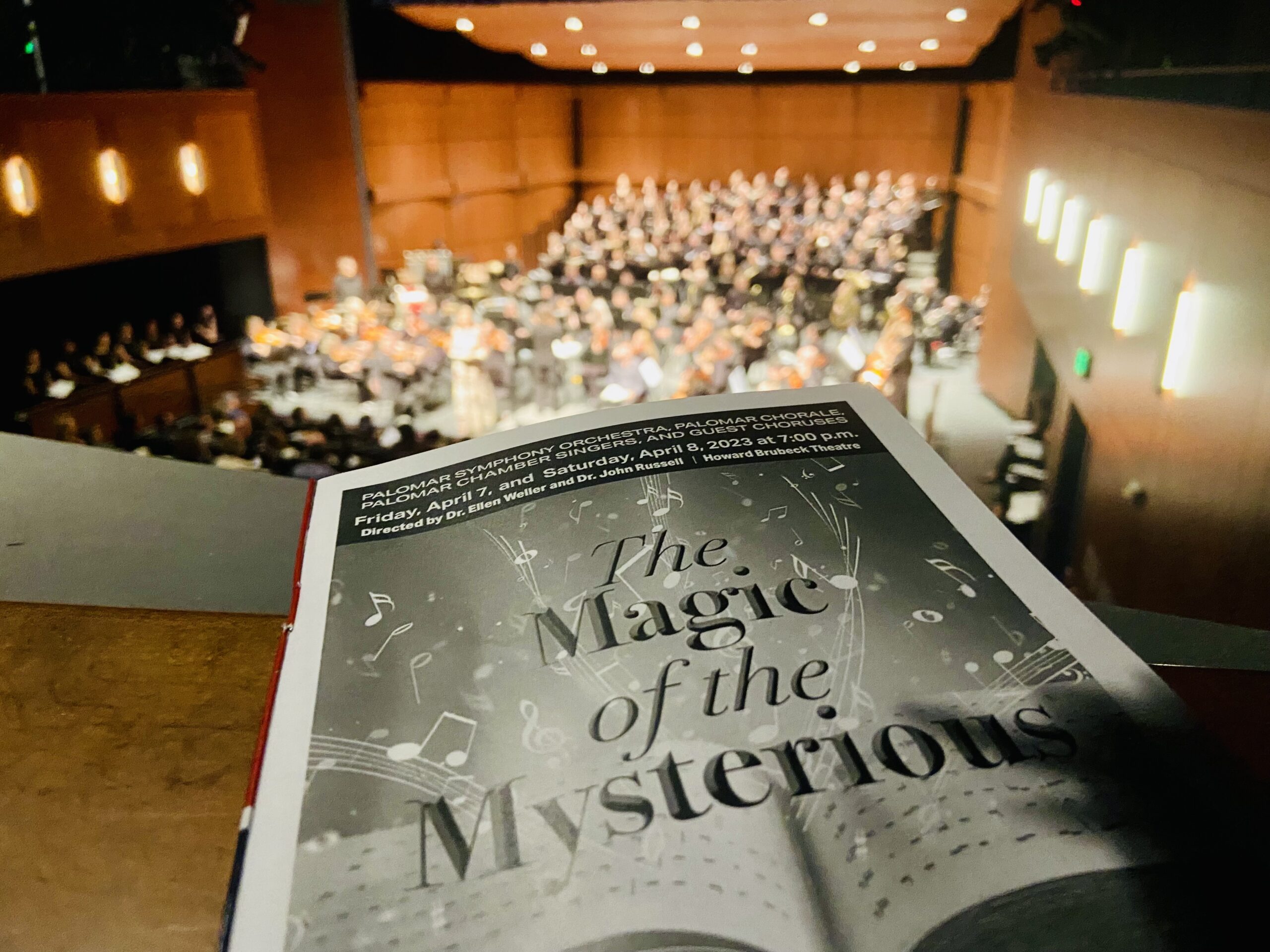 A pamplet of "The Magic of the Mysterious" lies on a ledge overlooking an orchestra below.