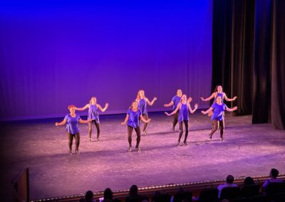 tap dancers in black pants and blue shirts performing on stage
