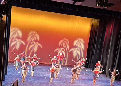 dancers in tribal wear spin poi with a tropical orange background