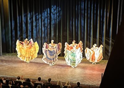 Dancers in traditional Mexican dresses performing on stage.