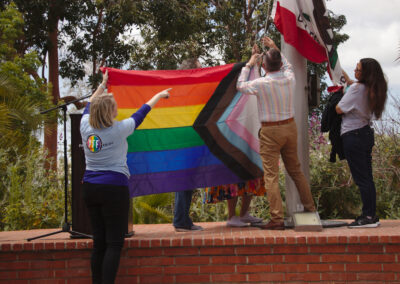 Palomar staff and faculty raise a Queer Pride flag at the Queer Pride campus event.