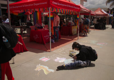 student drawing with chalk in front of tents